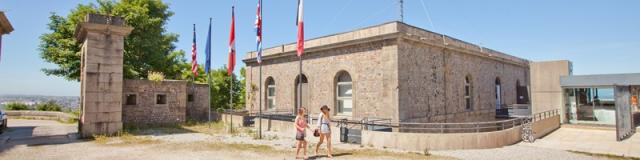Two people in front of a historic building with flags