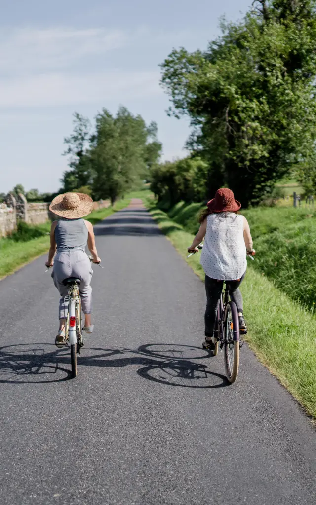 Deux personnes à vélo roulant sur une route de campagne entourée de verdure