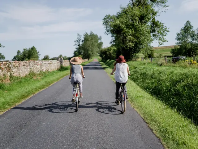 Deux personnes à vélo roulant sur une route de campagne entourée de verdure
