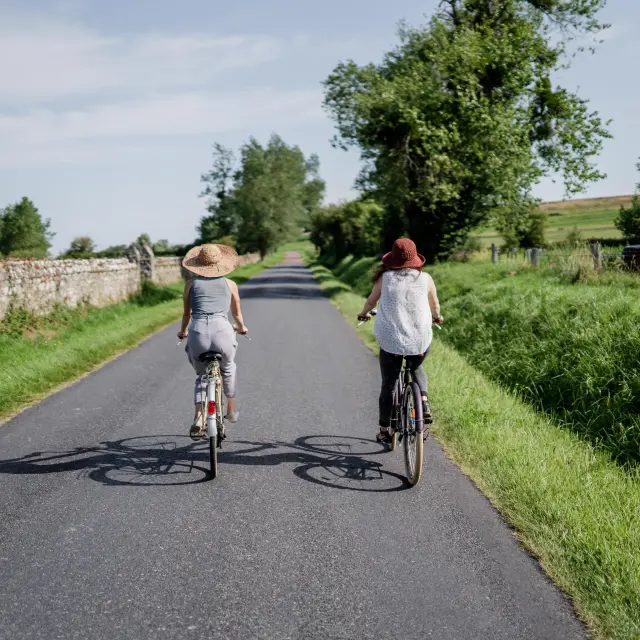 Deux personnes à vélo roulant sur une route de campagne entourée de verdure