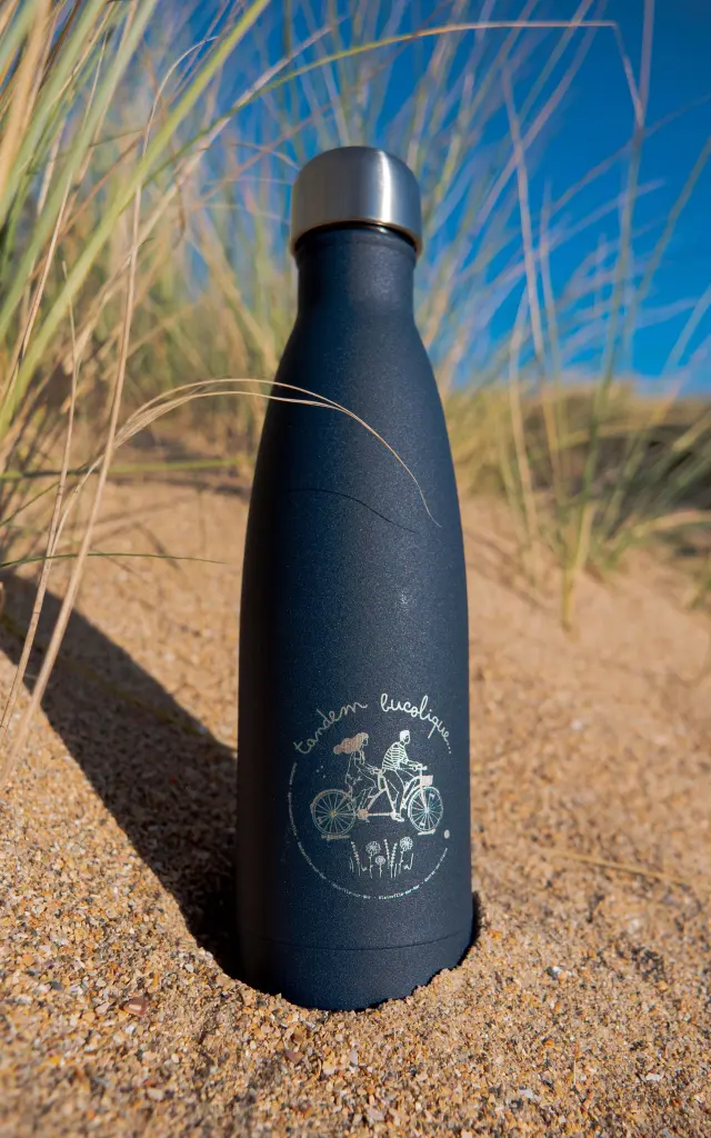 Gourde noire avec un design personnalisé posée sur le sable