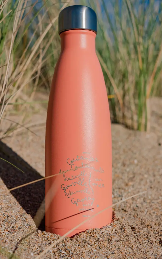 Gourde en métal orange avec texte personnalisé sur une plage