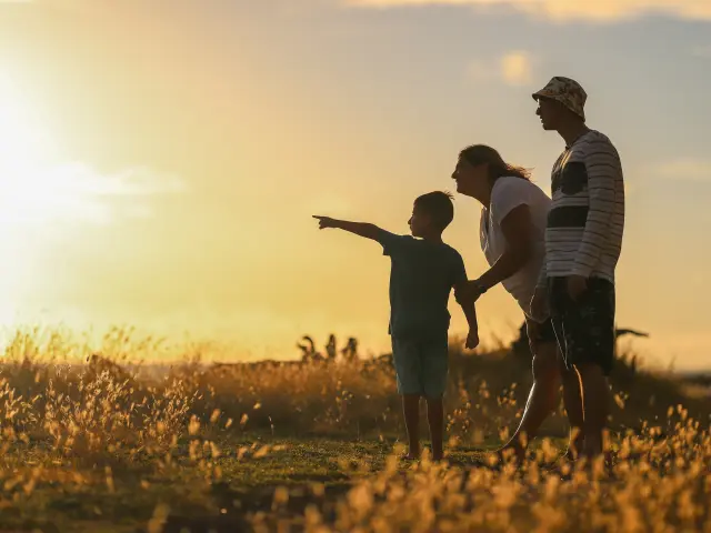 Une famille marche dans un champ au coucher du soleil