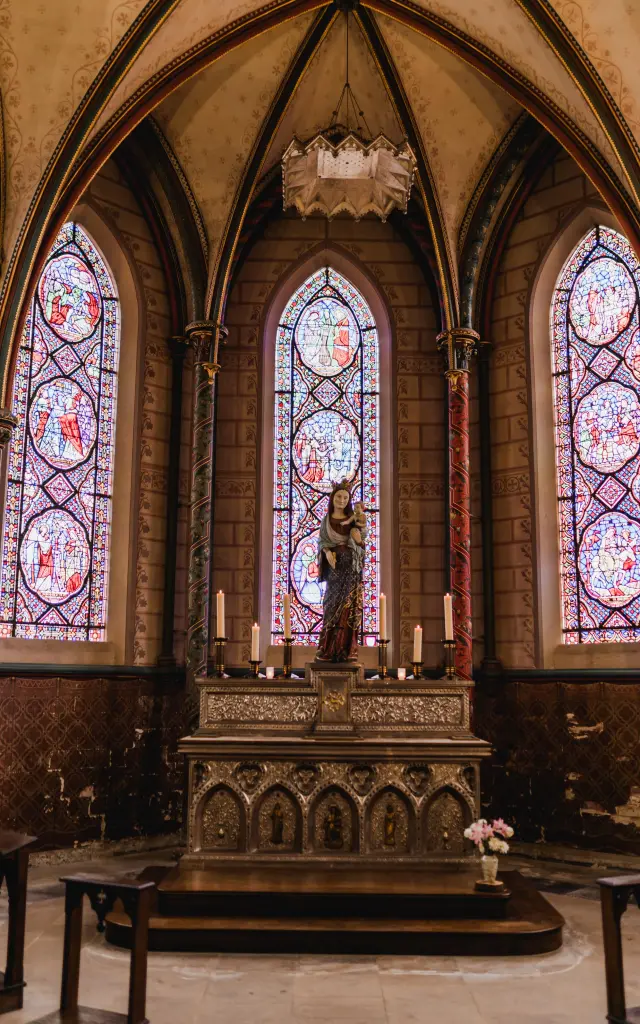 Autel avec des bougies et une statue devant des vitraux dans la cathédrale de Coutances