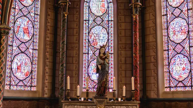 Autel avec des bougies et une statue devant des vitraux dans la cathédrale de Coutances