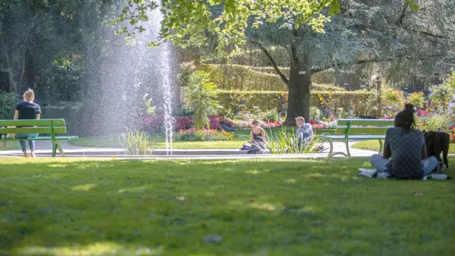 Personnes assises sur des bancs dans le jardin des plantes de Coutances