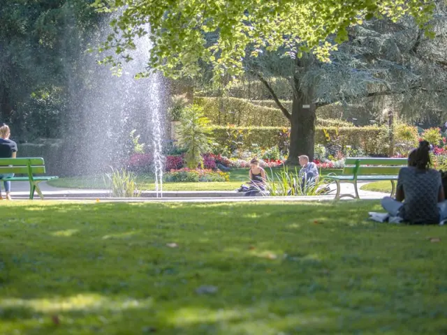 Personnes assises sur des bancs dans le jardin des plantes de Coutances