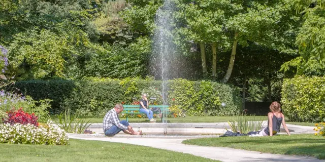 Trois personnes assises près d'une fontaine dans le jardin des plantes de Coutances
