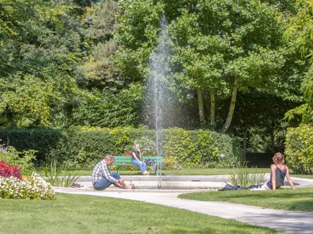 Trois personnes assises près d'une fontaine dans le jardin des plantes de Coutances