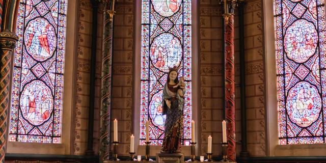 Autel avec des bougies et une statue devant des vitraux dans la cathédrale de Coutances