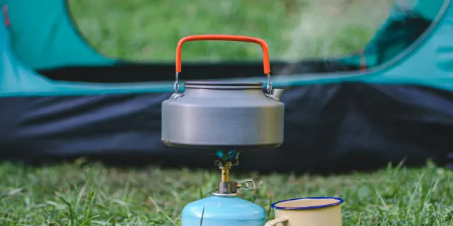 Tente de camping avec un réchaud à gaz et une tasse à côté