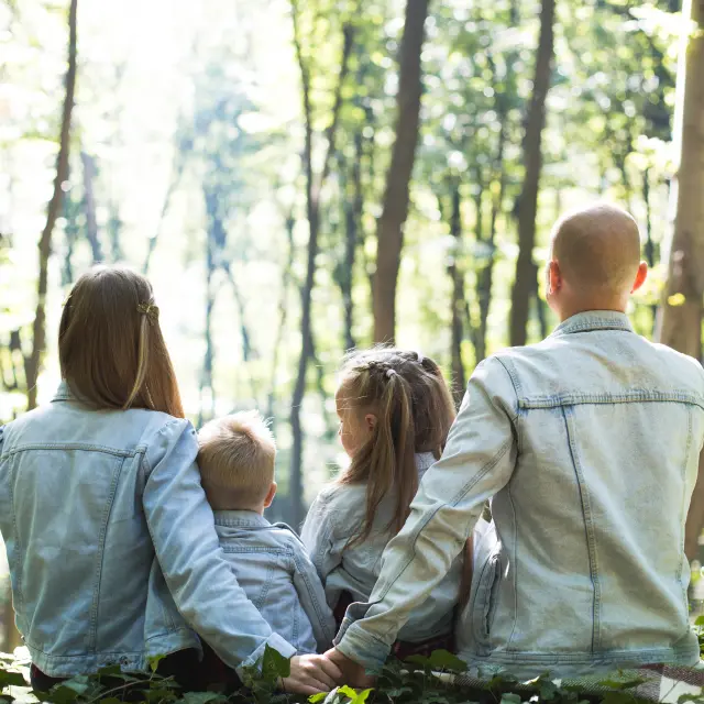 Une famille de quatre personnes assises dans une forêt