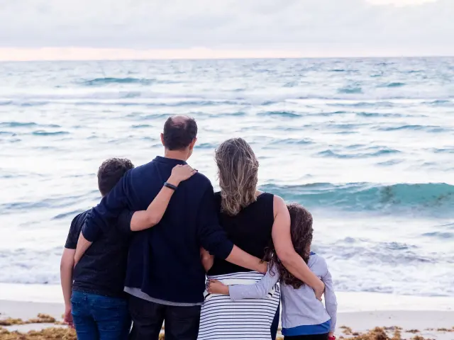 Une famille de quatre personnes se tient sur une plage face à l'océan
