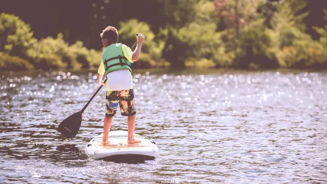 Enfant en paddle sur un lac avec une pagaie
