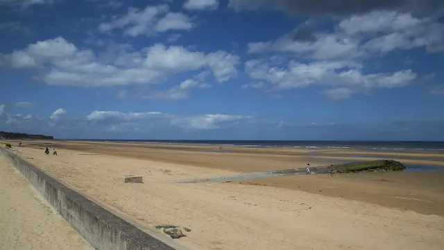 Sandstrand mit einigen Menschen in der Ferne und einem teilweise bewölkten Himmel