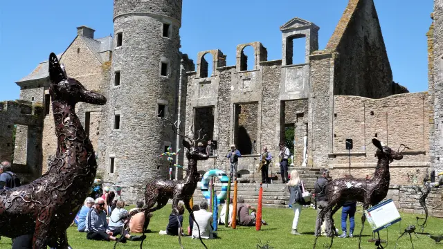 Metal deer sculptures in front of a ruined castle