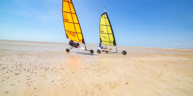 Deux Chars à voile avec des voiles jaunes sur une plage désertique