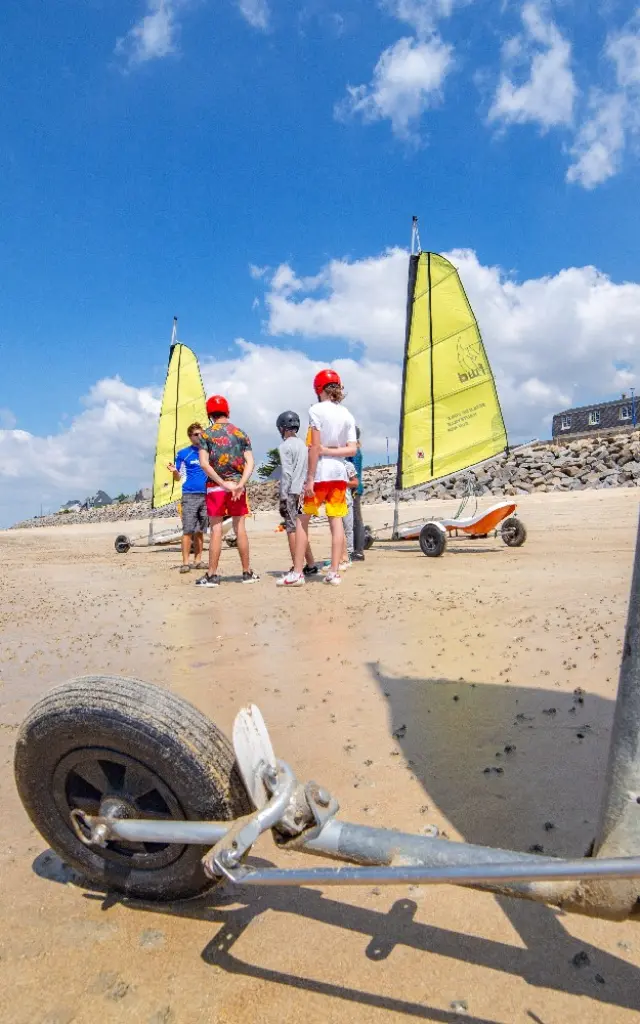 Groupe de personnes apprenant à utiliser des chars à voile sur une plage