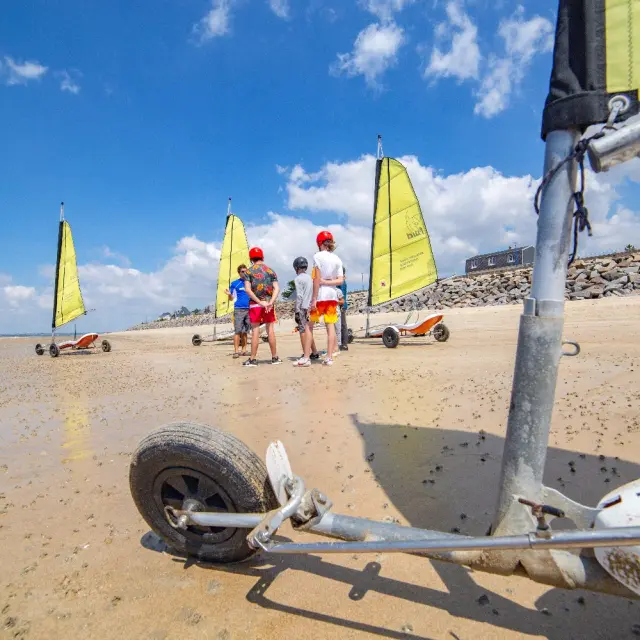 Groupe de personnes apprenant à utiliser des chars à voile sur une plage