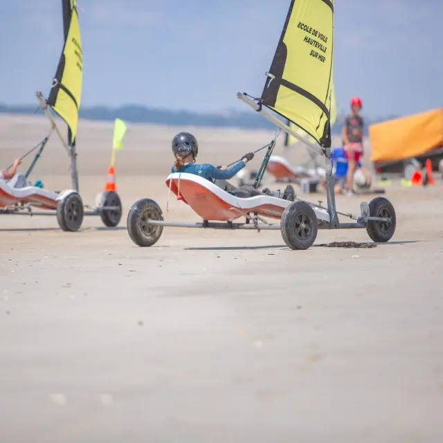 Deux personnes pilotant des chars à voile sur une plage