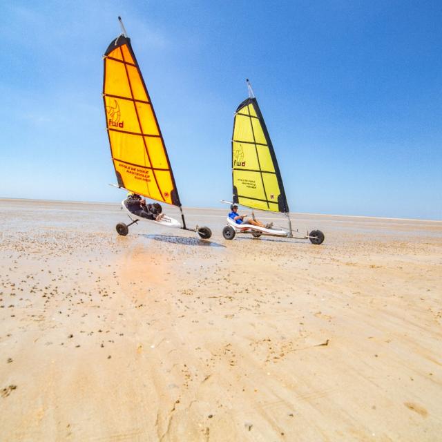 Two land sailors with yellow sails on a deserted beach
