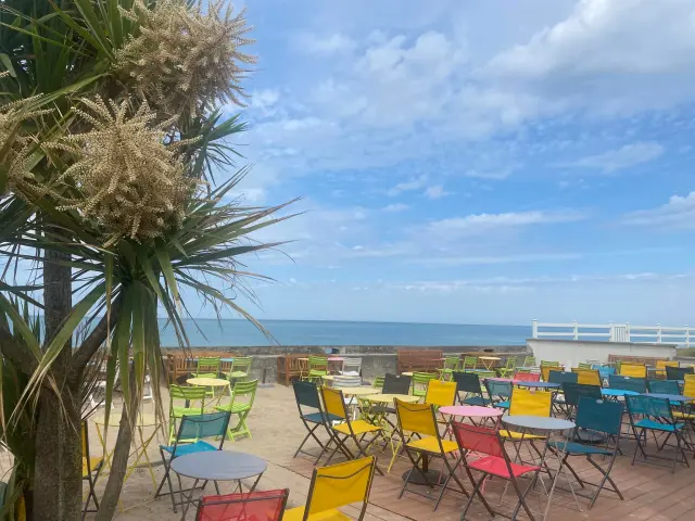 Terrasse avec des chaises colorées face à la mer : La mer Ô vent à Hauteville sur Mer