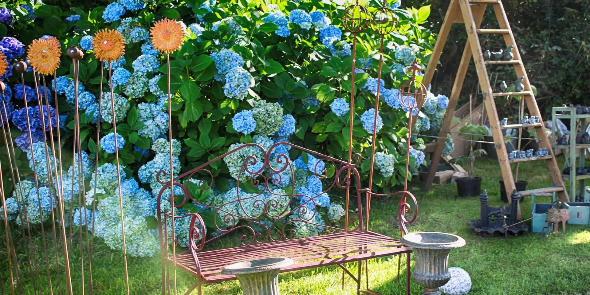 Un banc en fer forgé dans un jardin avec des fleurs bleues : A propos de Jardin au chateau de Gratot