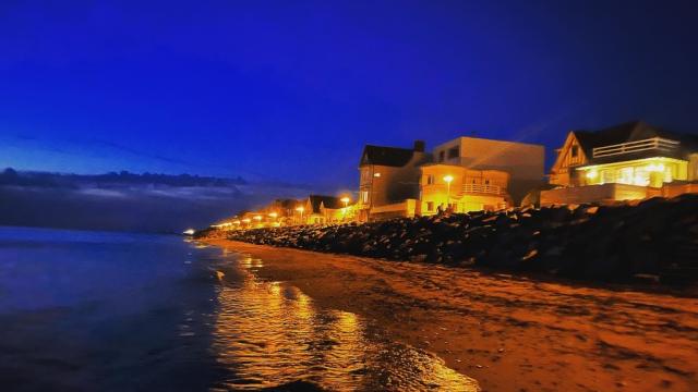 Plage de nuit avec des maisons éclairées et des vagues