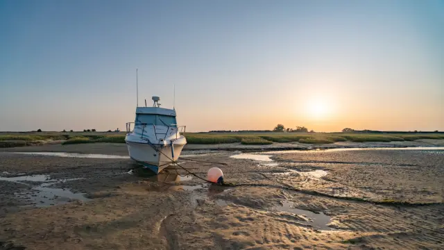 A white boat stranded on a sandy beach at sunset