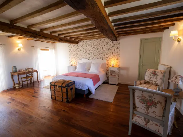 Chambre avec lit, chaise, table et décoration rustique au manoir des Loges à Quettreville sur Sienne
