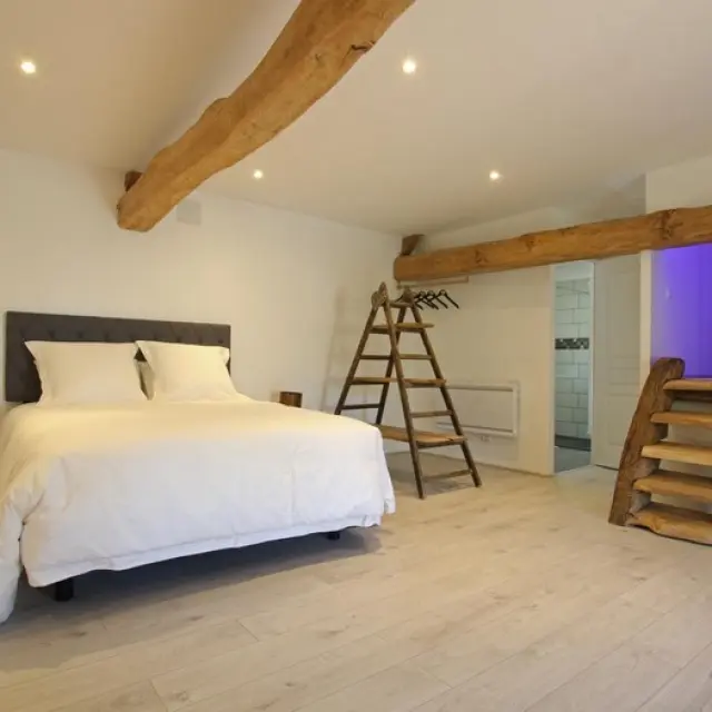 Chambre à coucher avec lit blanc, escalier en bois et grande fenêtre : Les Gabriolleries de COurcy