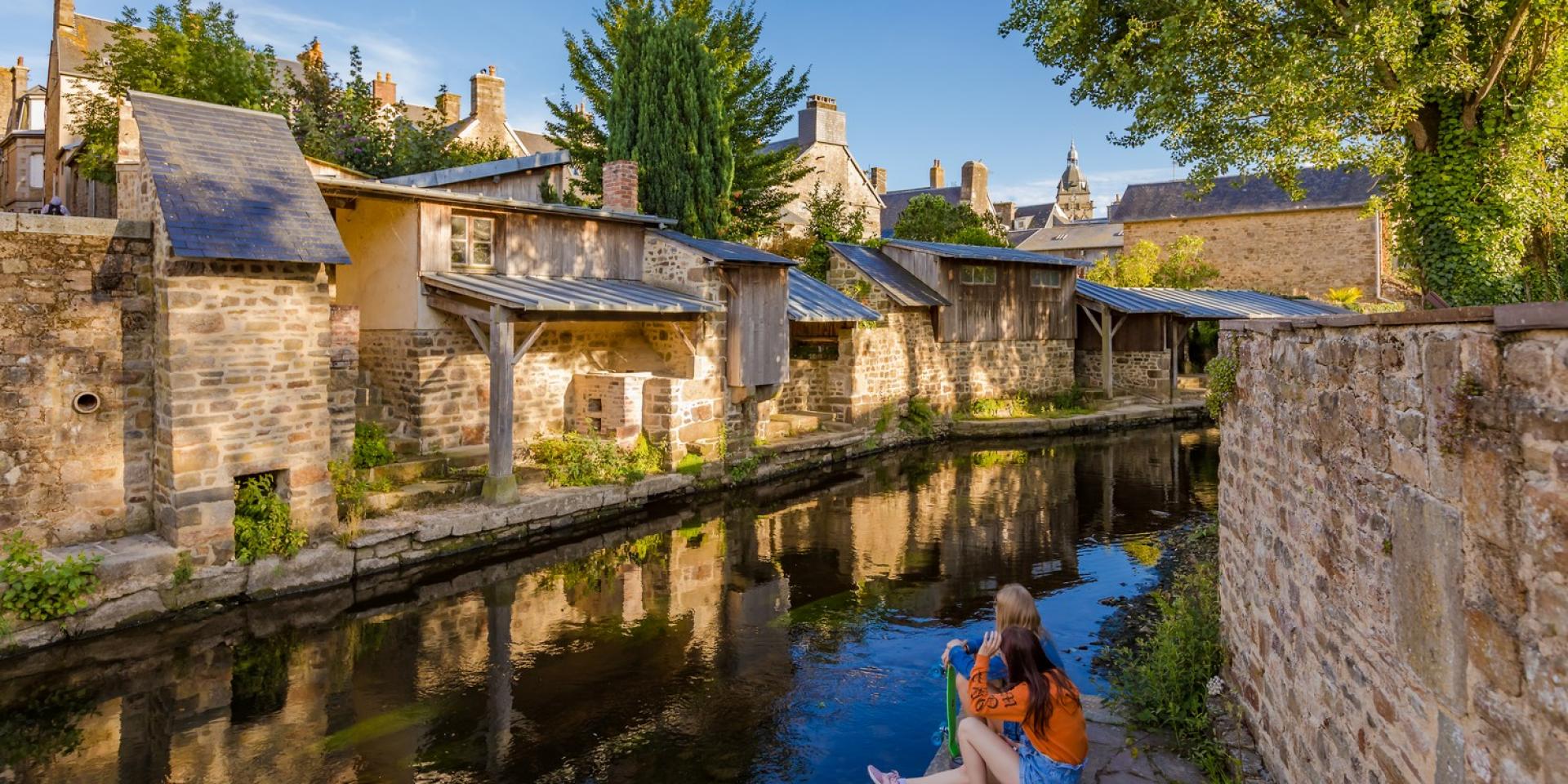 A person sitting by the edge of a canal in a picturesque village