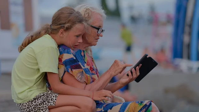 Une jeune fille et une personne âgée regardent un smartphone ensemble