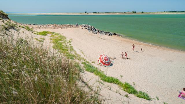 Une plage de sable fin avec des gens marchant le long de la côte