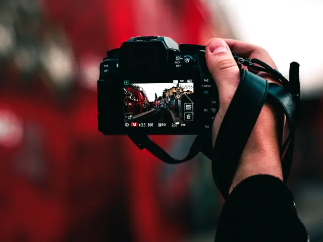 Main tenant un appareil photo numérique avec une scène urbaine à l'écran