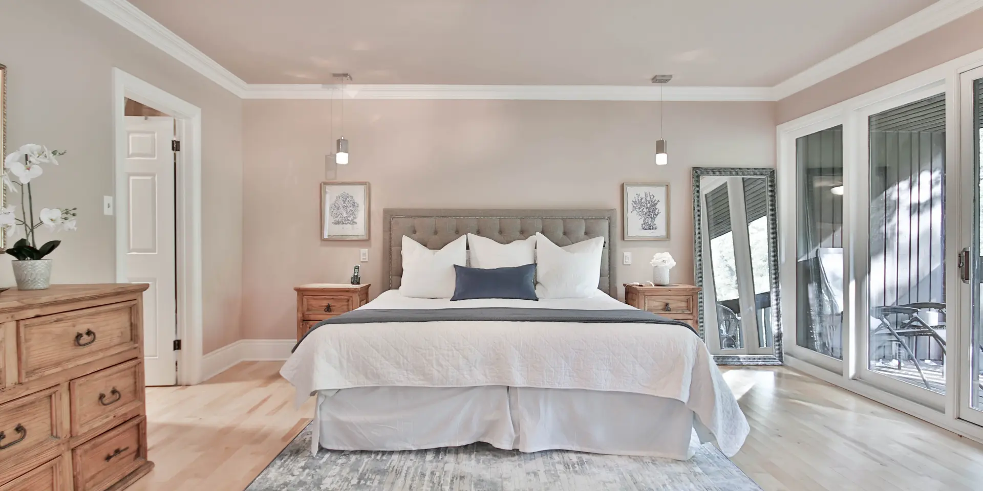 Chambre avec lit double, deux tables de chevet, un grand miroir et une porte-fenêtre
