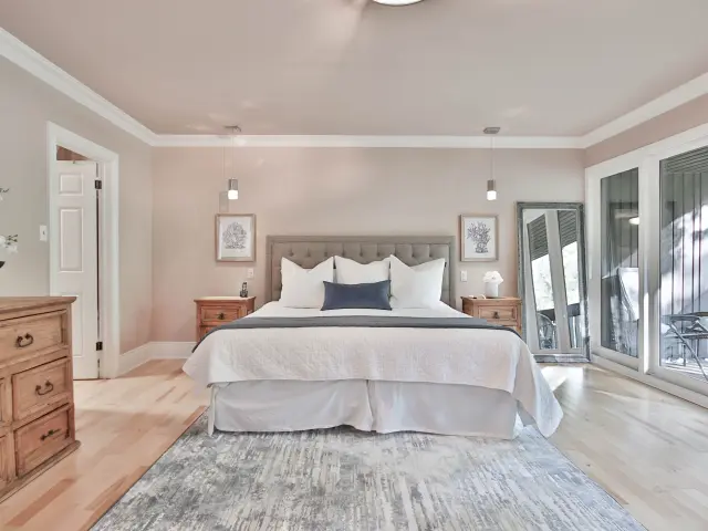 Chambre avec lit double, deux tables de chevet, un grand miroir et une porte-fenêtre