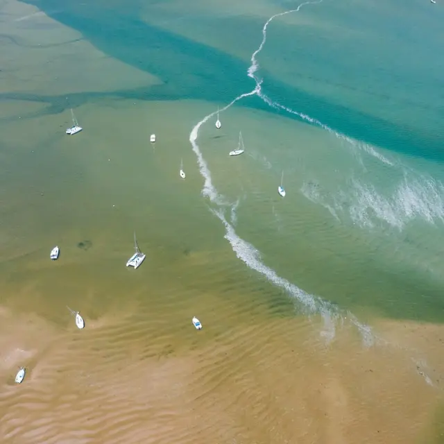 Several boats sailing on a shallow body of water