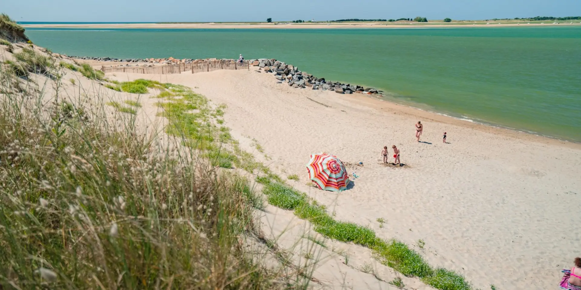 Une plage de sable fin avec des gens marchant le long de la côte