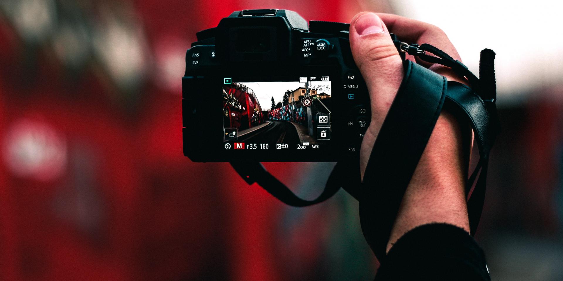 Main tenant un appareil photo numérique avec une scène urbaine à l'écran