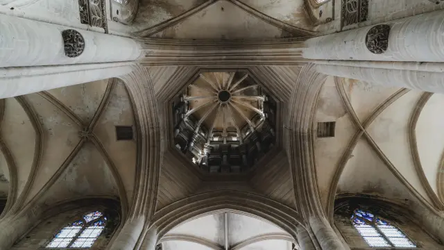 Vue vers le haut d'une voûte gothique avec des arcs et des vitraux dans la cathédrale de Coutances