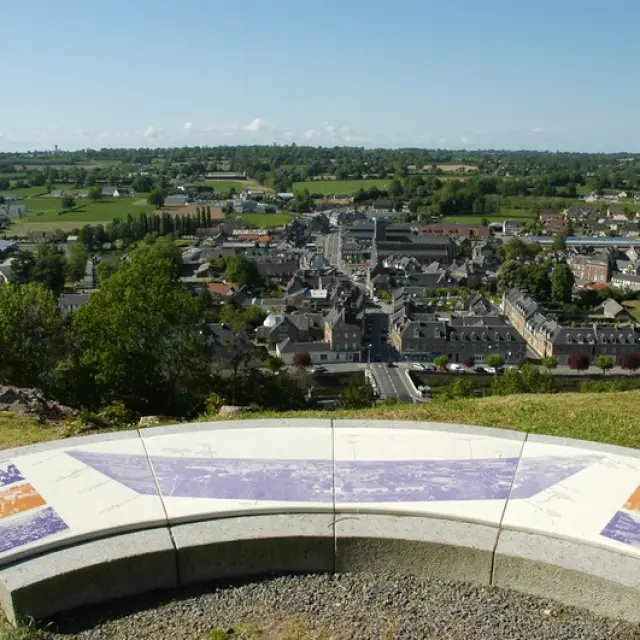 Panoramablick auf eine Stadt von einem Hügel mit einer Bank im Vordergrund