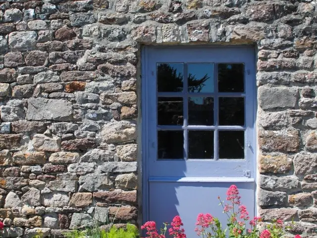 Blue door with a six-pane window in a stone wall