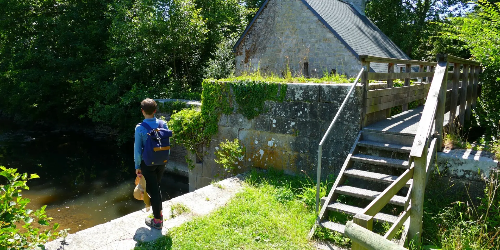 Person geht auf ein abgelegenes Haus in der Nähe eines Bachs zu