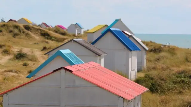 Femme marchant sur dans les dunes et cabines de Gouville sur Mer