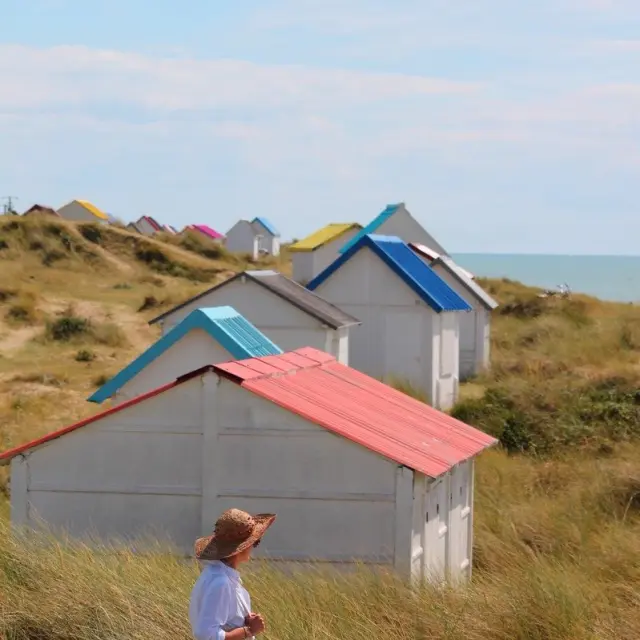 Femme marchant sur dans les dunes et cabines de Gouville sur Mer