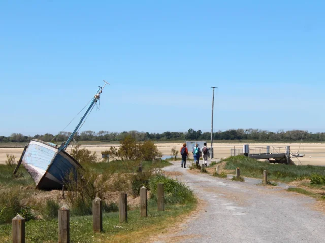 Hikers walking on a path near a stranded boat