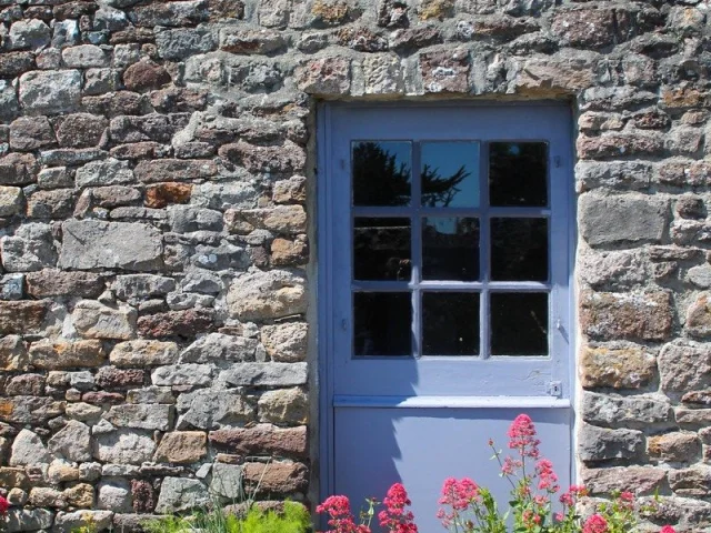 Blue door with a six-pane window in a stone wall
