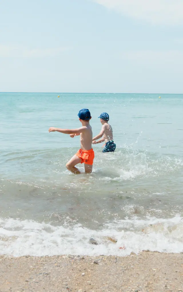 Deux enfants jouent dans les vagues de l'océan