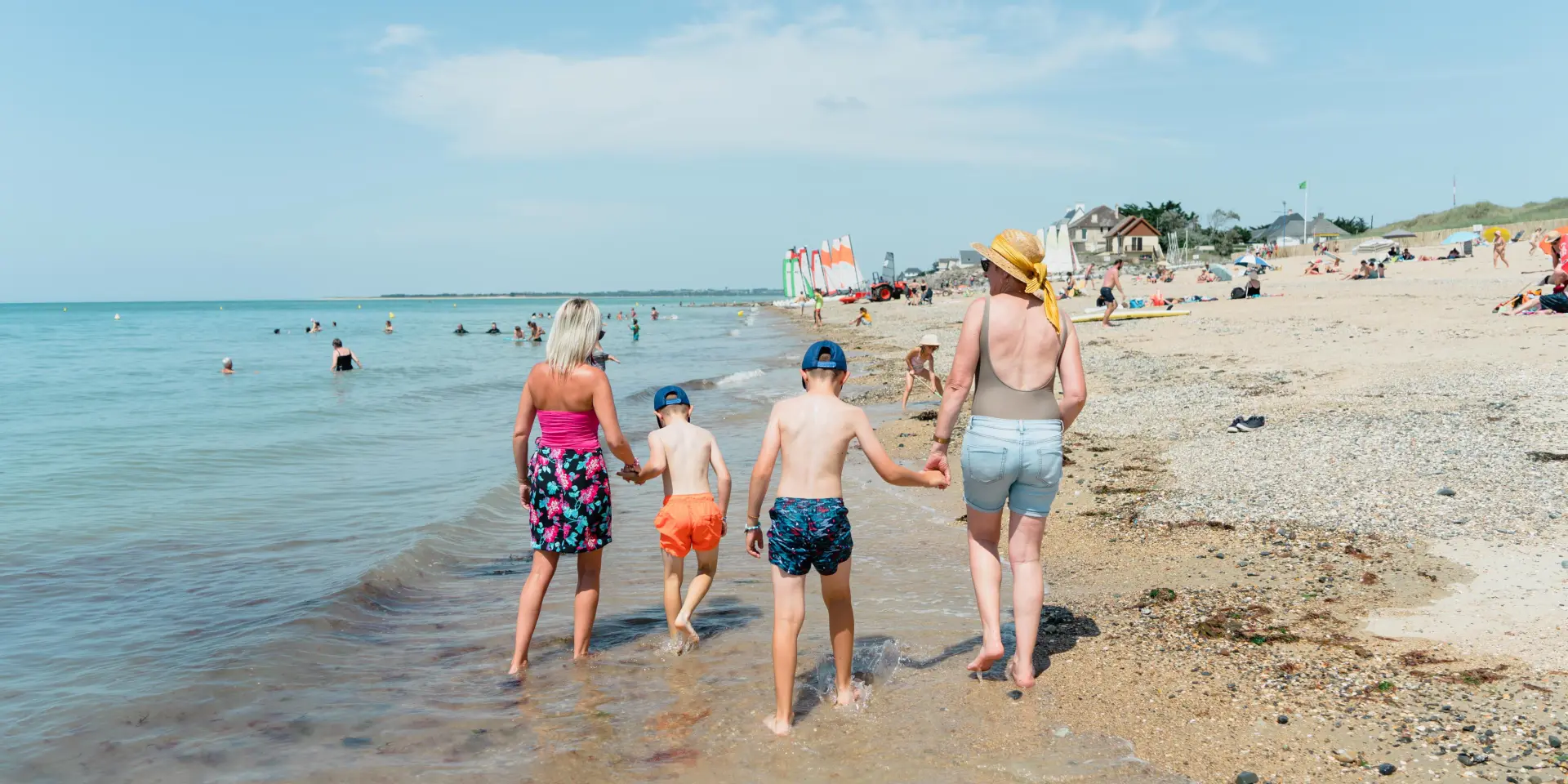 Une famille marche le long de la plage avec deux enfants entre les parents